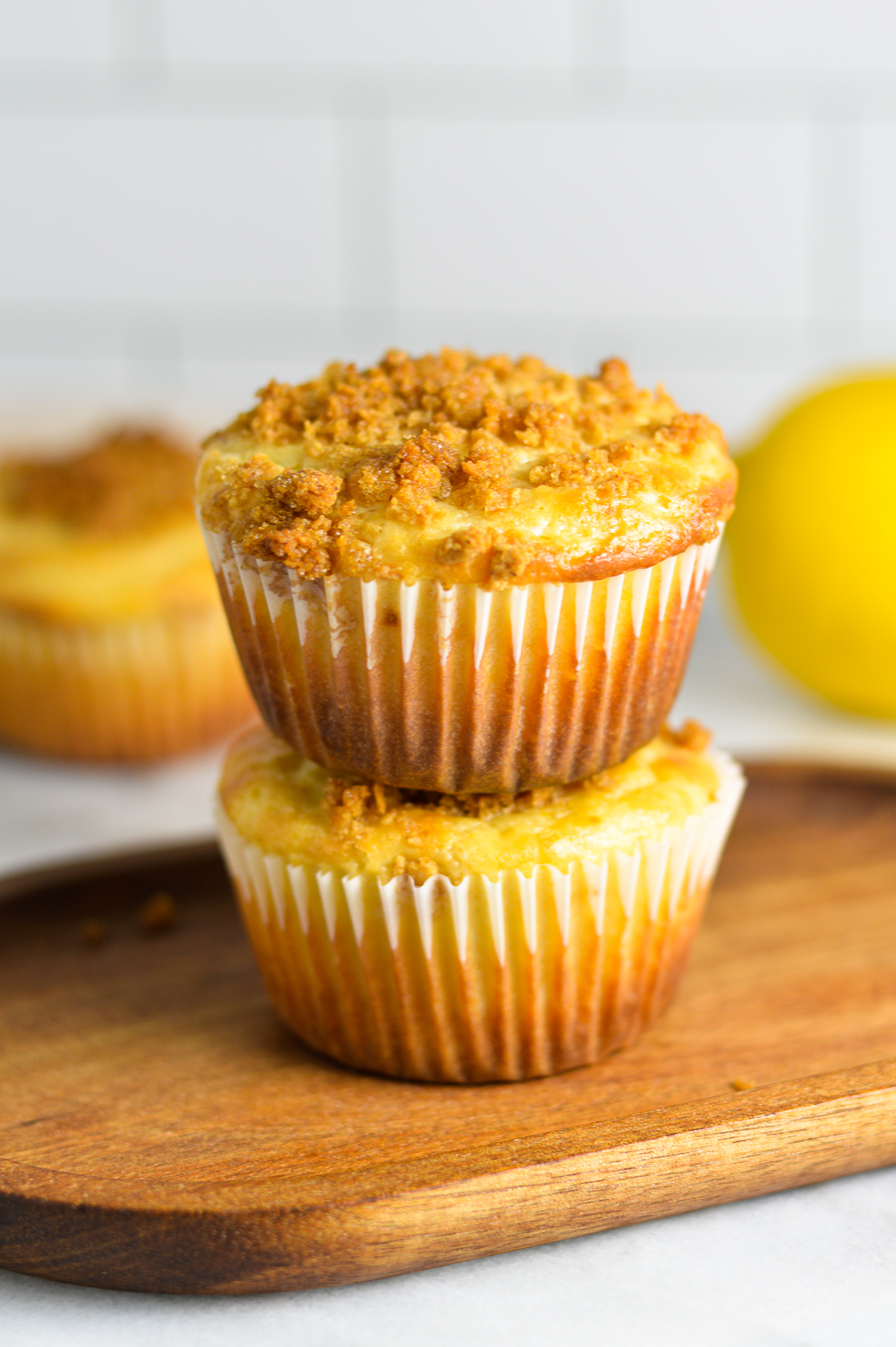 A stack of two Lemon Muffins on a wooden slab.