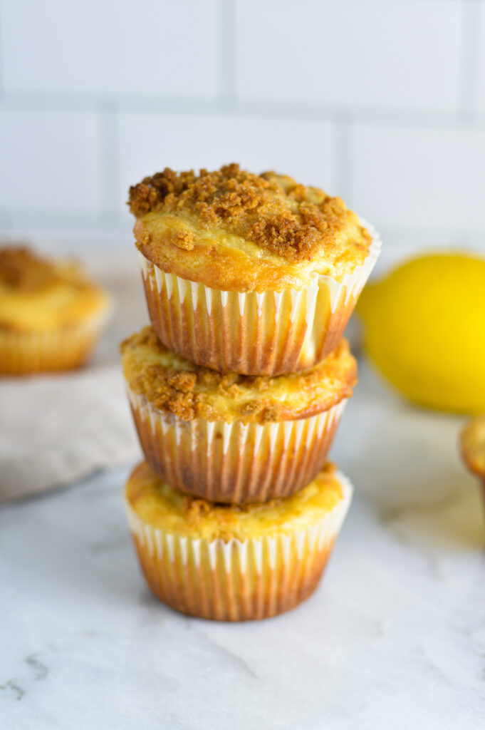 A stack of 3 soft Lemon Muffins on a granite surface.