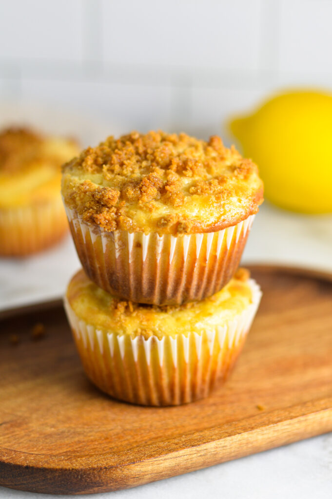 Two moist Lemon Streusel Muffins on a small wooden board.