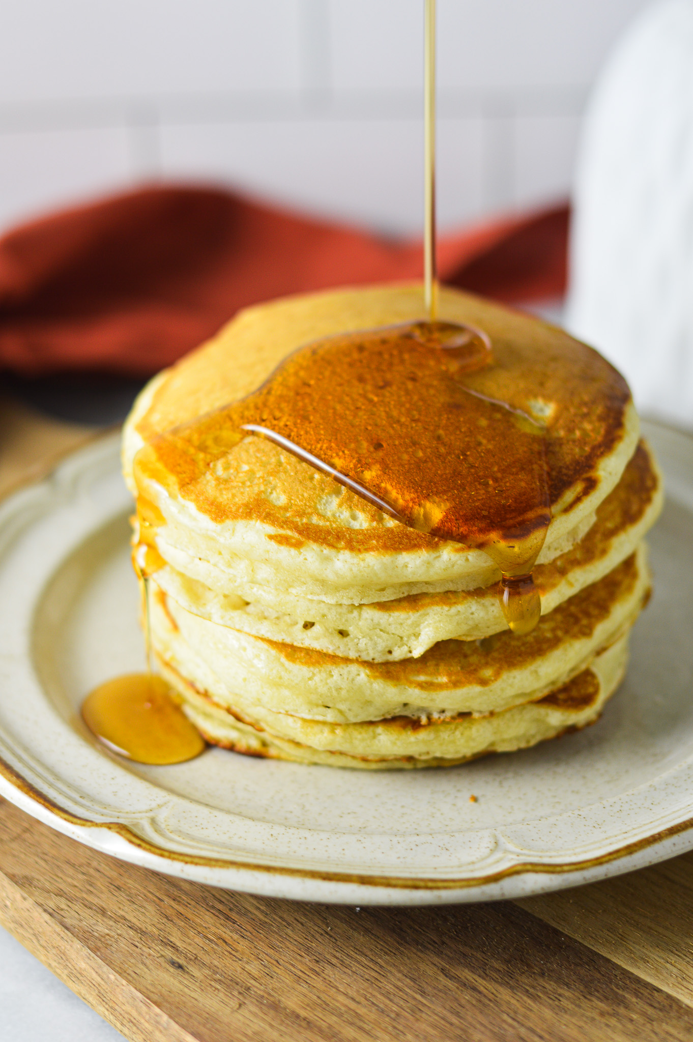 A stack of golden Plain Pancakes, with a drizzle of maple syrup coating the top.