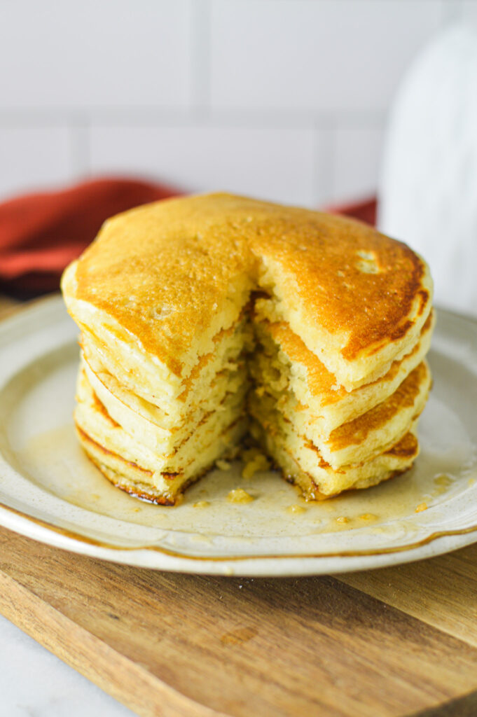 A stack of Plain Pancakes with a triangle slice taken out, showing the fluffy center.