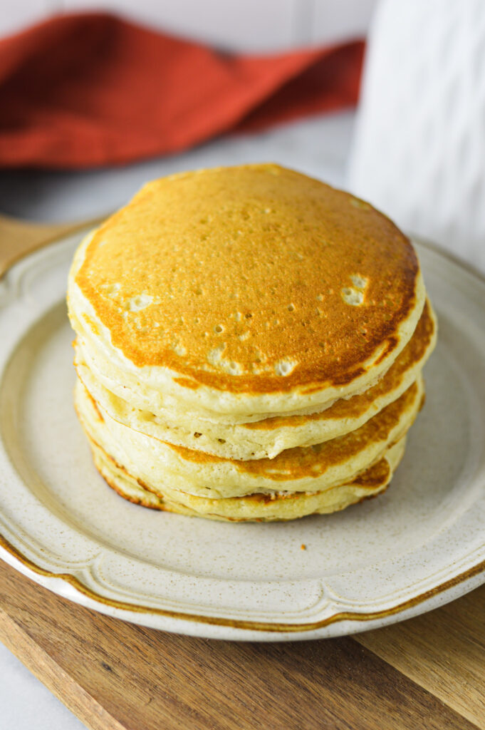 A stack of Plain Pancakes arranged in a stack on a small white plate.