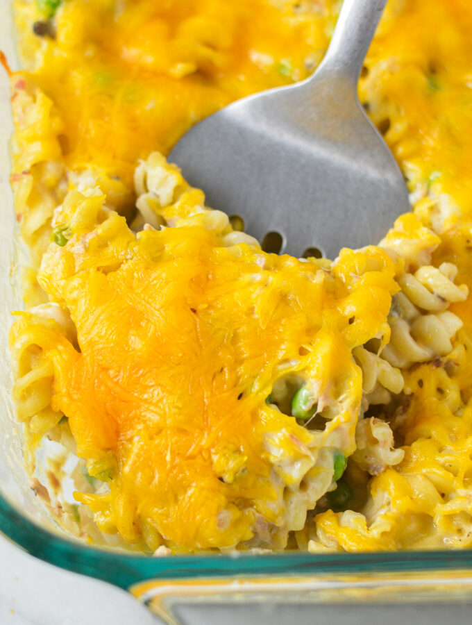 A large glass baking dish with a spatula scooping some Tuna Casserole.