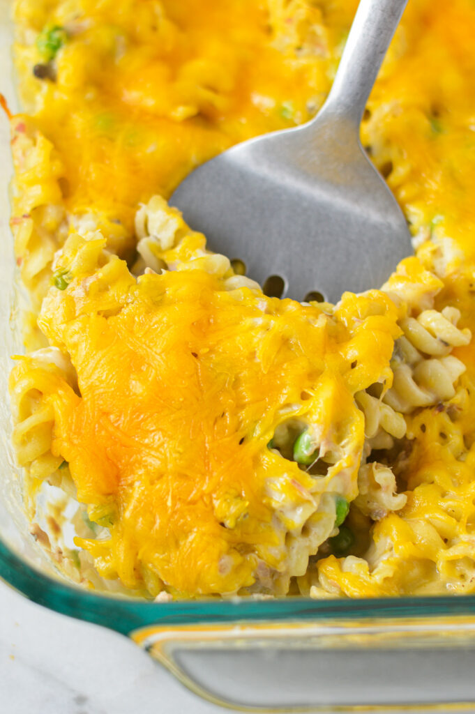 A large glass baking dish with a spatula scooping some Tuna Casserole.