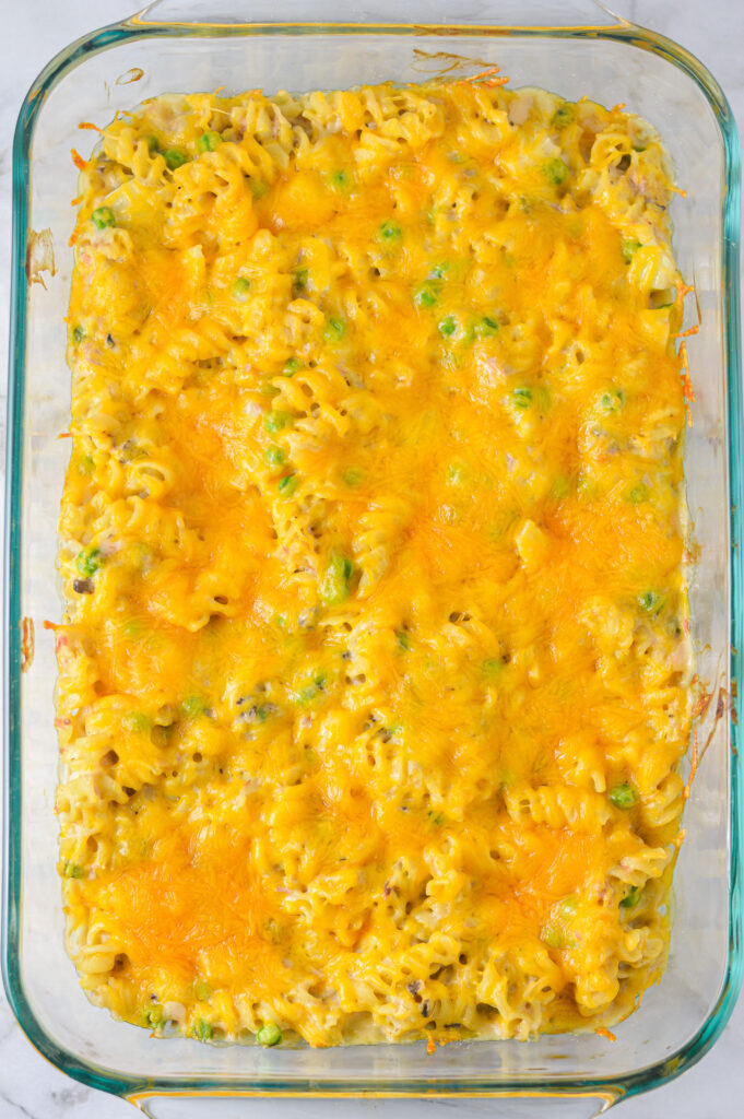 A large baking dish filled with hearty Tuna Casserole, with Fusilli noodles poking through the melted cheese.