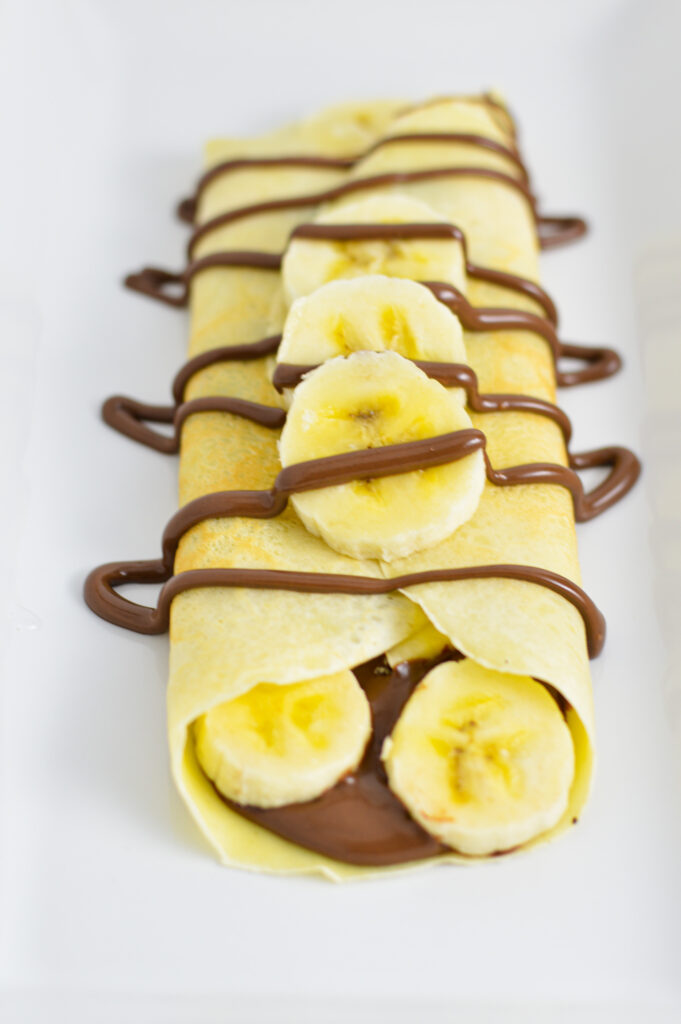 A Banana Nutella Crepe with bananas and Nutella drizzle on top.