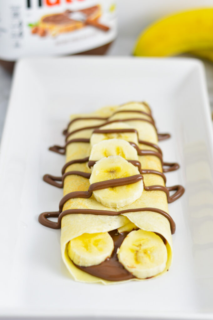 Soft Nutella Banana Crepes on a long white square plate.