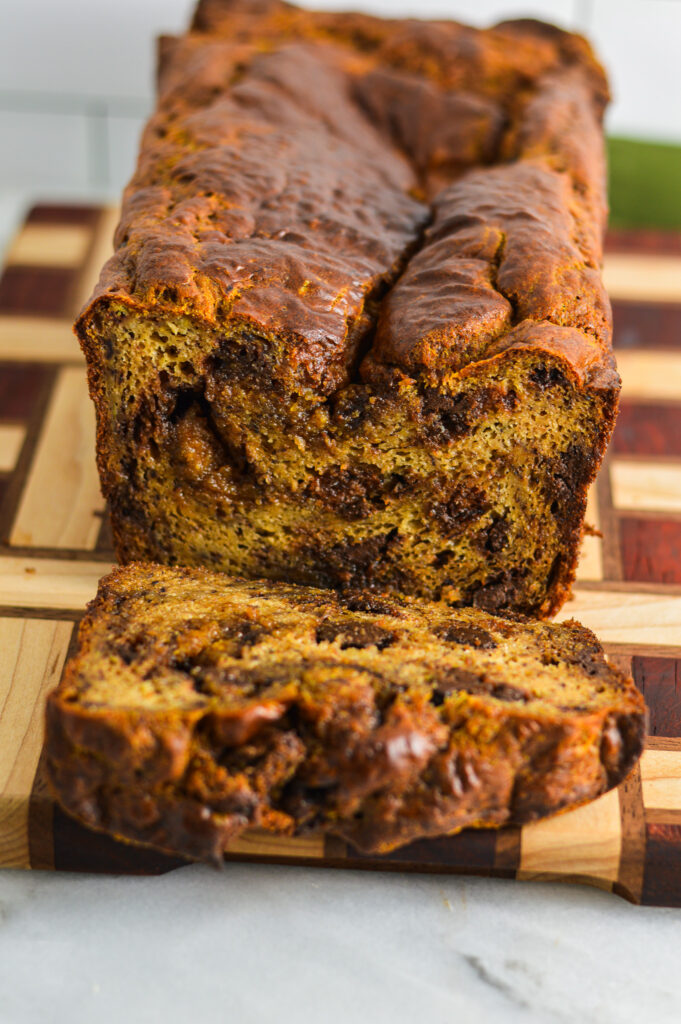 A loaf of Peanut Butter Cup Banana Bread cut on a checkered cutting board.