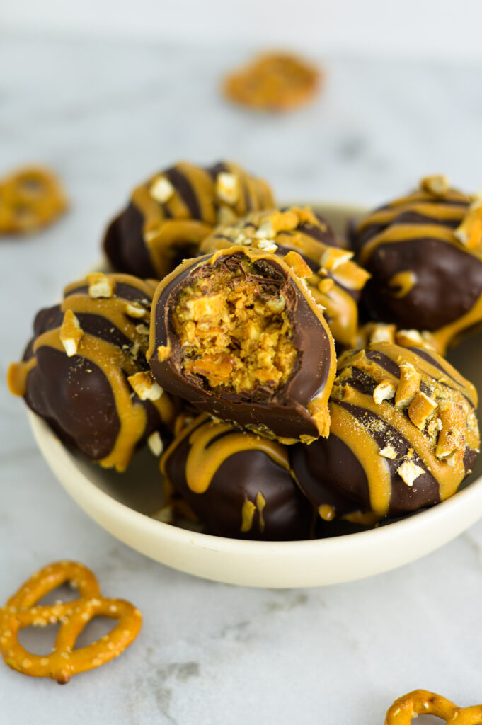 A small bowl of Peanut Butter Pretzel Truffles with mini pretzels in the background.