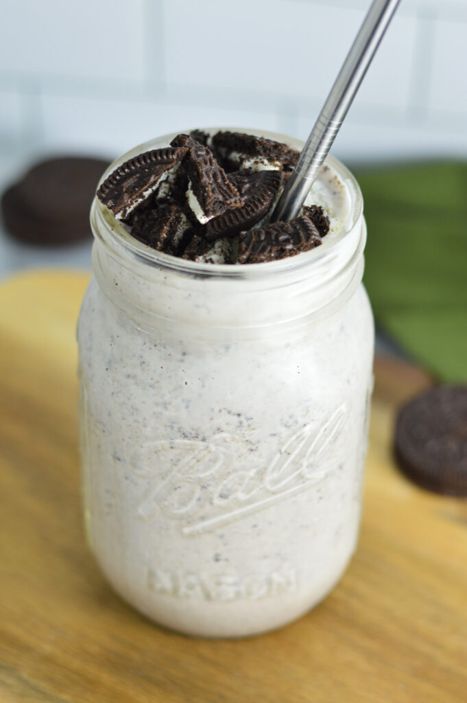 An Oreo Milkshake in a mason jar with crushed Oreo on top.