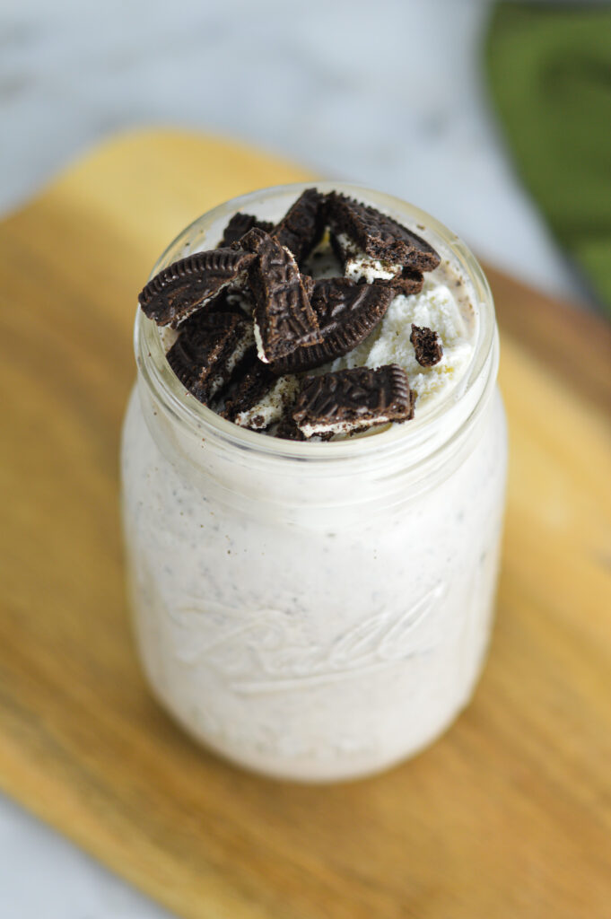 Creamy Oreo Milkshake in a glass on a wooden board.