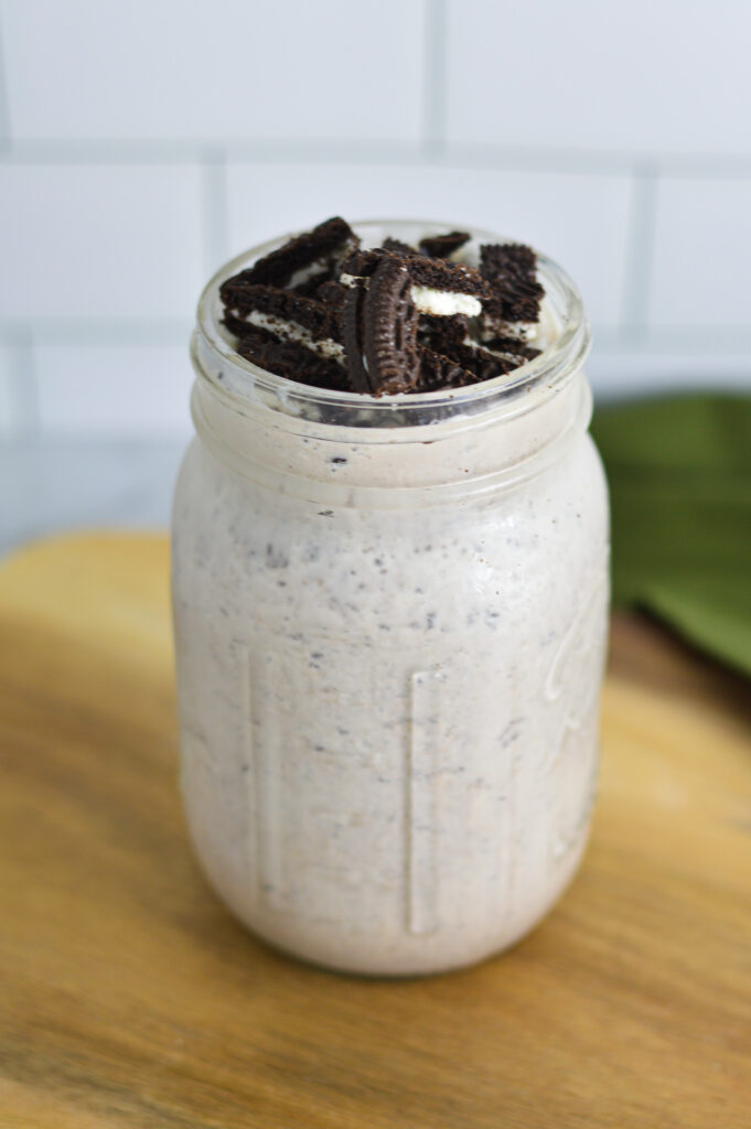 Smooth Oreo Milkshake in a tall glass with crumbled Oreo on top.