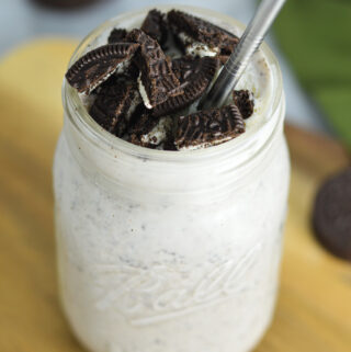 Oreo Milkshake with Oreo pieces on top and a straight metal straw in it.