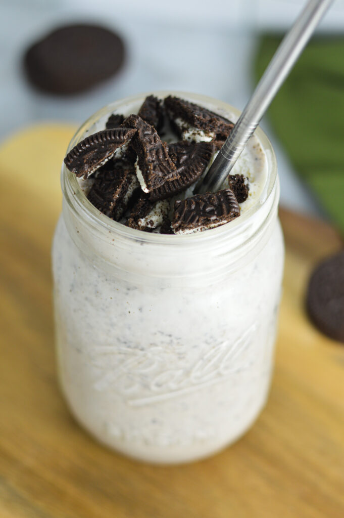 Oreo Milkshake with Oreo pieces on top and a straight metal straw in it.