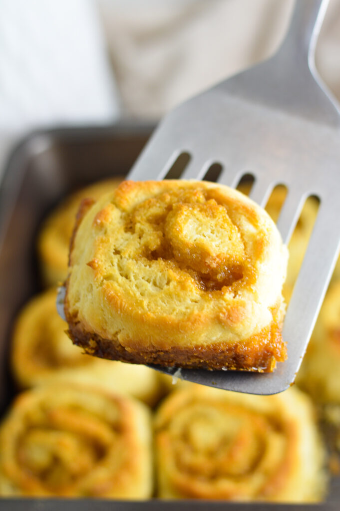 A metal spatula holding a butterscotch pinwheel.