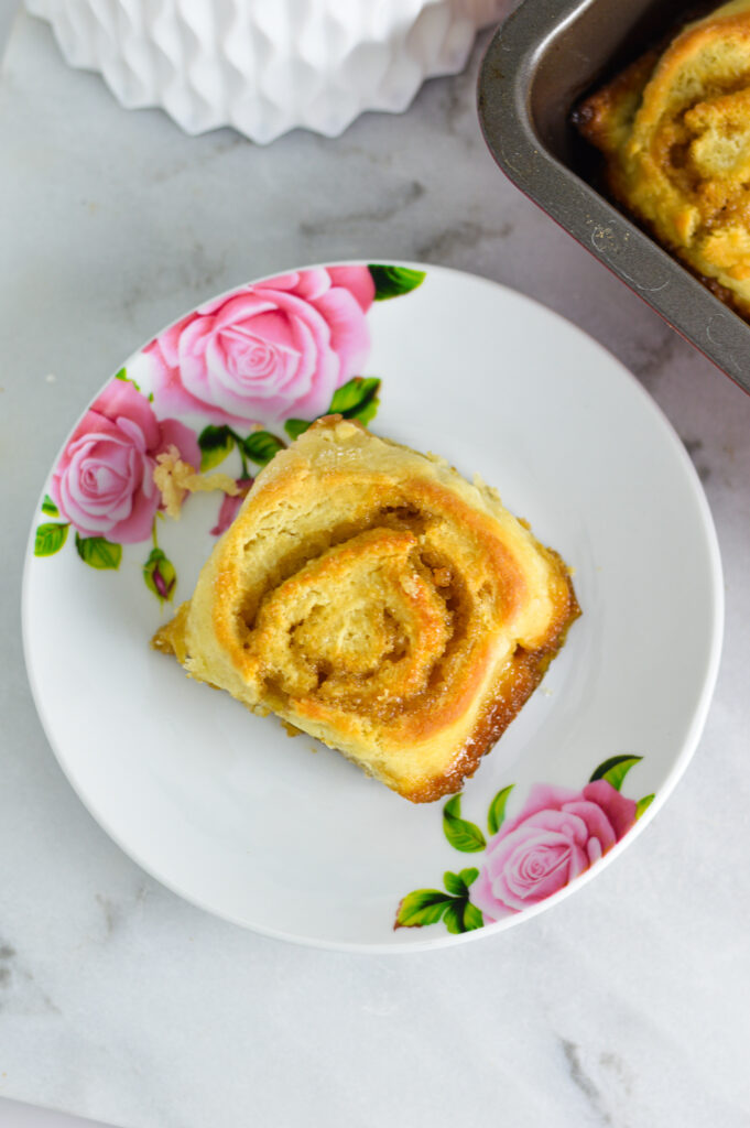 A butterscotch pinwheel on a small white plate with flowers.