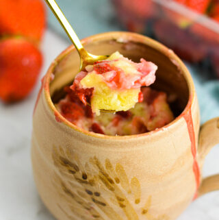 Strawberry Mug Cake with a gold spoon taking a piece out.