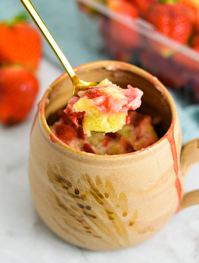 Strawberry Mug Cake with a gold spoon taking a piece out.