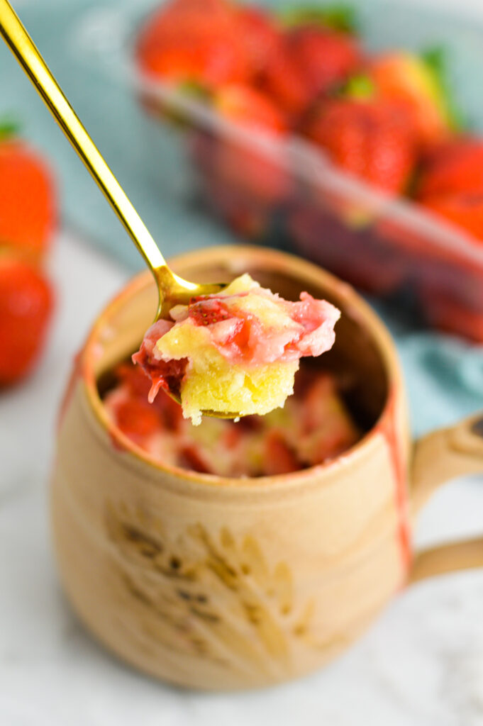 A small spoonful of Strawberry Mug Cake on a gold spoon.