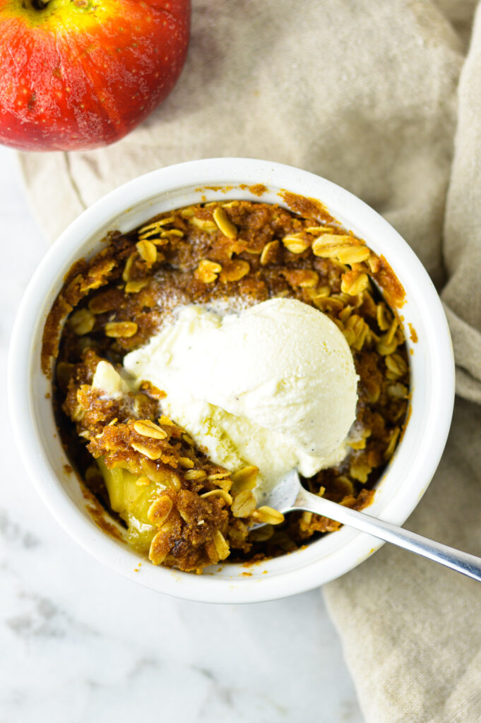 5 Minute Apple Crisp for One with a scoop of vanilla ice cream on top.