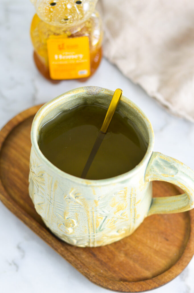 Apple Cider Vinegar Tea in a large coffee mug with a bear shaped bottle of honey in the background.