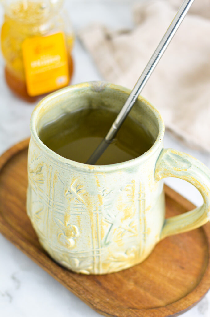 Apple Cider Vinegar Tea in a large light green mug with a metal straw in it.