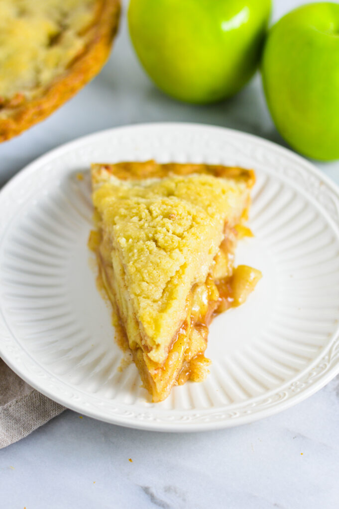 A slice of Butter Crumble Apple Pie on a small white plate.