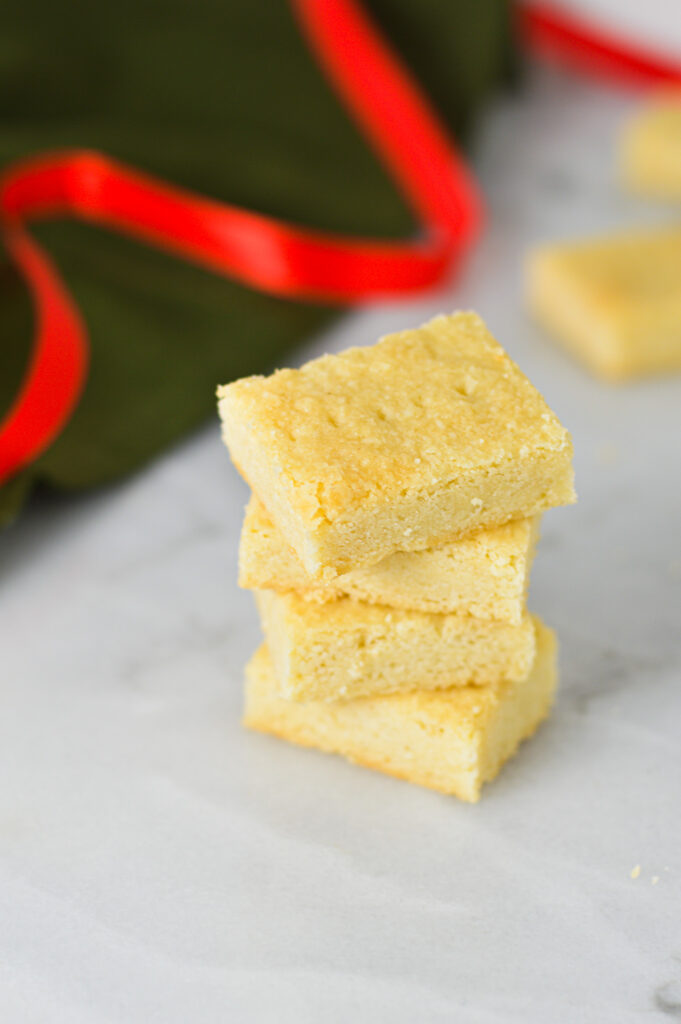 A stack of Shortbread Cookies on a granite surface, with some red Christmas ribbon in the background.