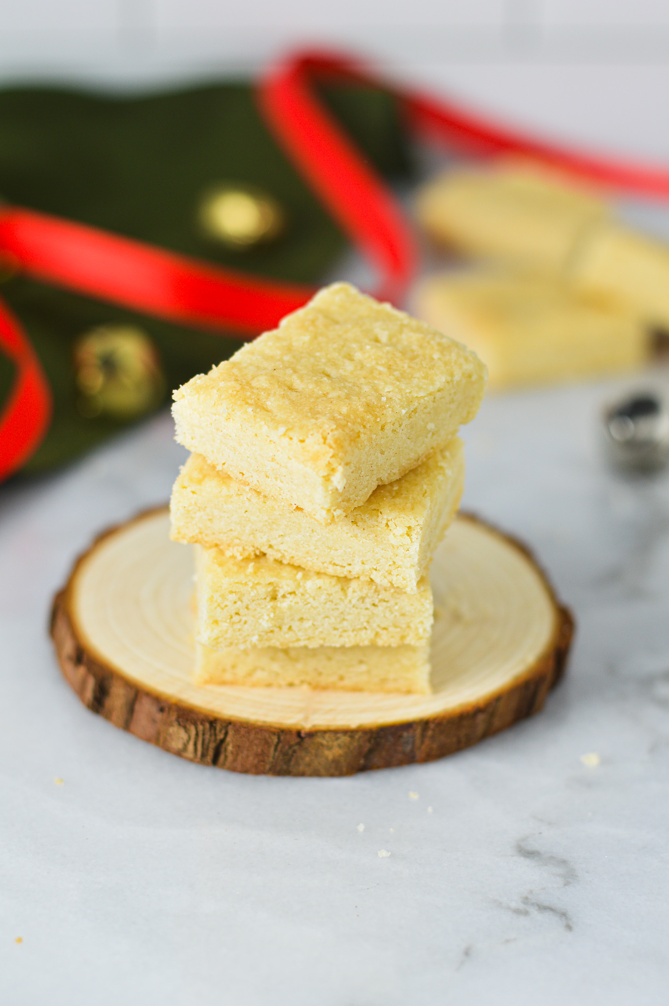 A stack of Shortbread Cookies cut into small rectangles, with Christmas decorations in the background.