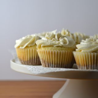 Super moist vanilla cupcakes with vanilla frosting. A surprise cookie is baked on the bottom of the cupcakes to make them extra special.