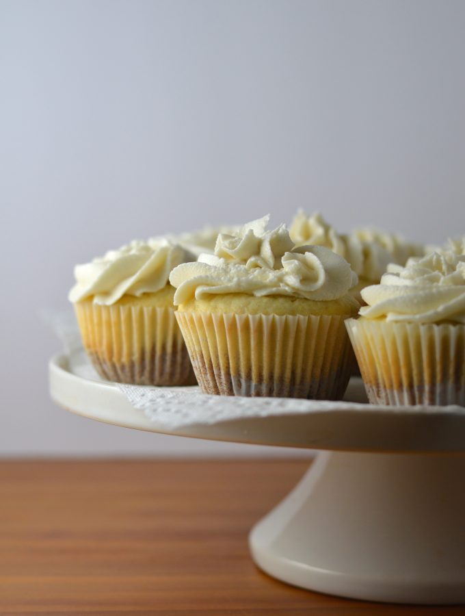 Super moist vanilla cupcakes with vanilla frosting. A surprise cookie is baked on the bottom of the cupcakes to make them extra special.