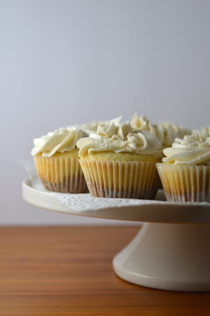 Super moist vanilla cupcakes with vanilla frosting. A surprise cookie is baked on the bottom of the cupcakes to make them extra special.