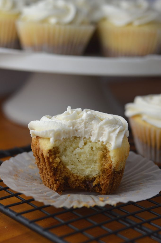 Super moist vanilla cupcakes with vanilla frosting. A surprise cookie is baked on the bottom of the cupcakes to make them extra special.