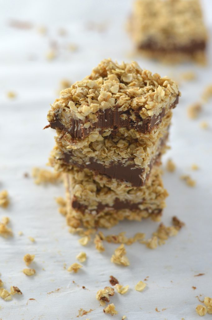 A stack of No Bake Peanut Butter and Chocolate Oat Fudge Bars on a granite surface with a bite taken out. 