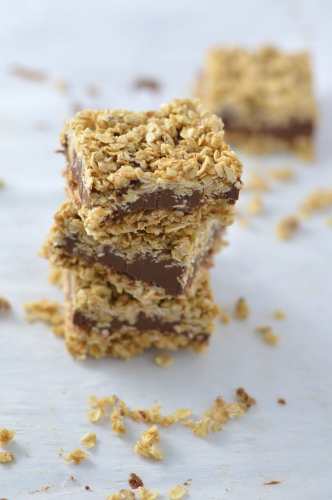 A stack of no bake peanut butter bars with a chocolate layer and a oat layer on top.