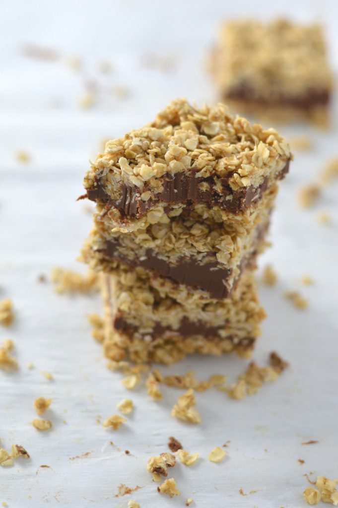 A stack of 3 oatmeal fudge bars with a bite taken out of the top oatmeal bar.