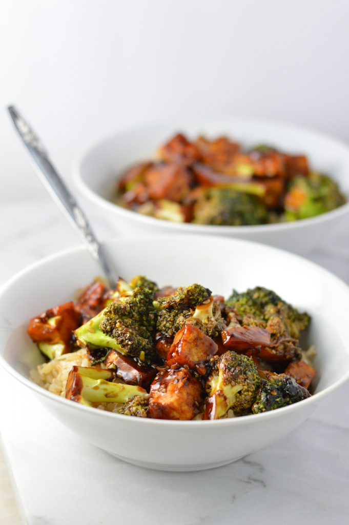 Side view of 2 bowls of Tofu Sesame Broccoli Stir Fry with a spoon in the first bowl.