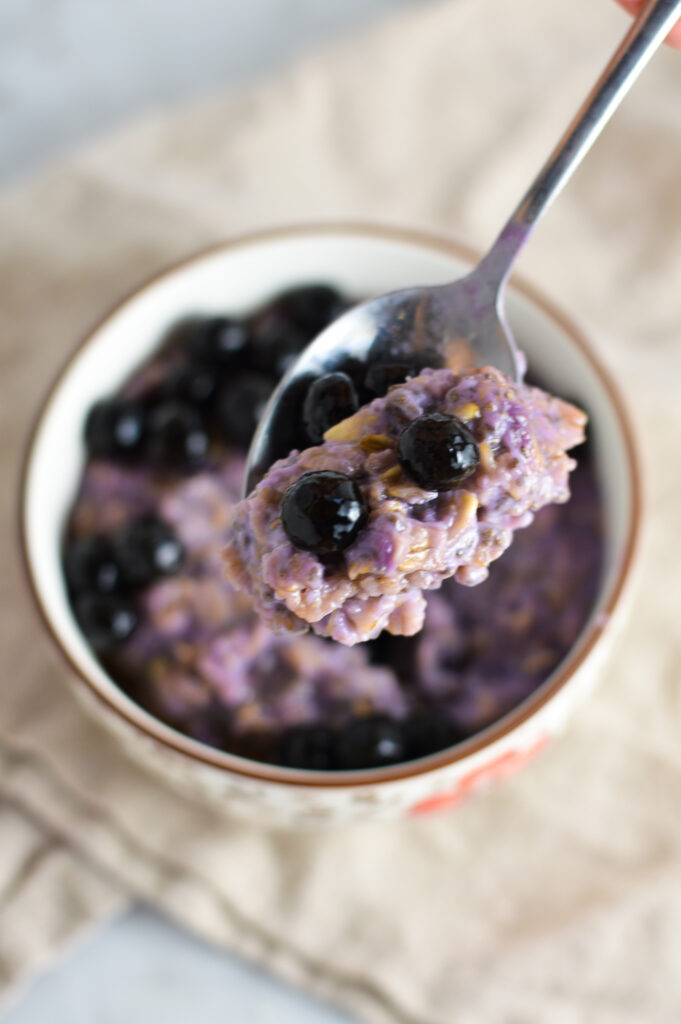 A spoon holding a scoop of Taro Bubble Tea Oatmeal.