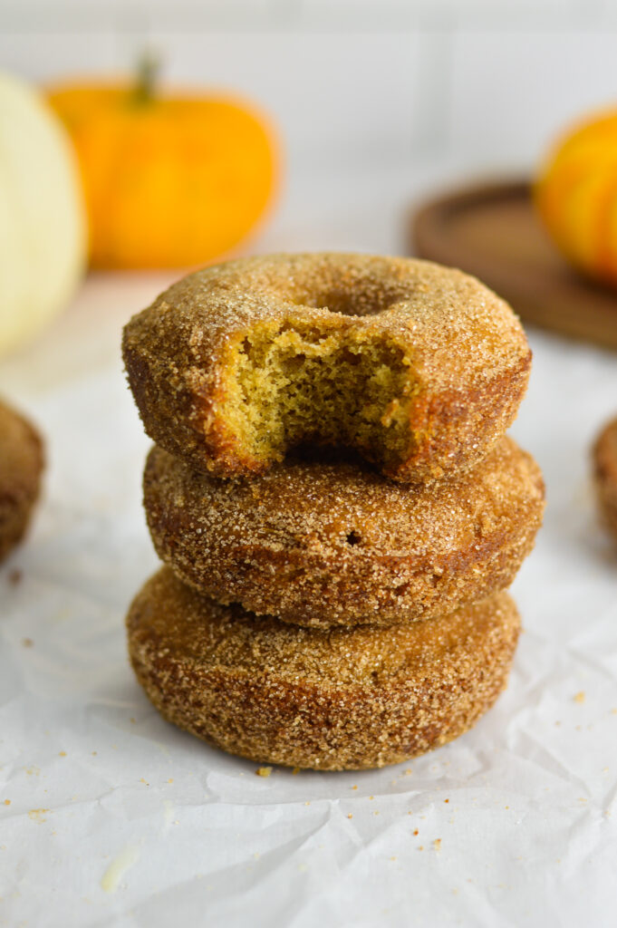 A stack of Baked Apple Cider Donuts with a bite taken out of the top doughnut.