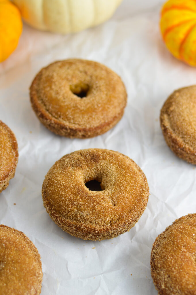 Baked Apple Cider Donuts laid flat on parchment paper.