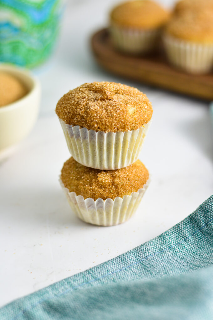 Two Churro Mini Muffins stacked with a pinch bowl of cinnamon sugar in the background.