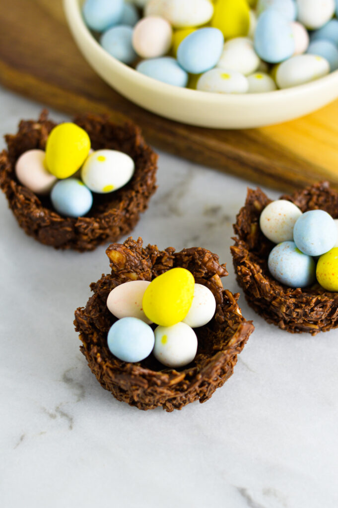 3 Almond Joy Easter Egg Nests with a bowl of Mini Eggs in the background.