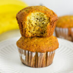 Two fluffy Banana Muffins stacked with a bite taken out of the top muffin.