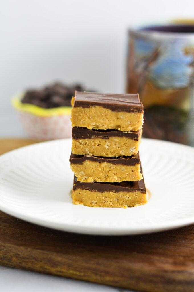 A stack of layered Chocolate Peanut Butter Squares on a small white plate.