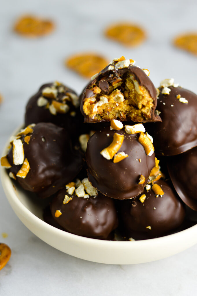 Crunchy Peanut Butter Pretzel Truffles in a bowl with a bite taken out of the top truffle.