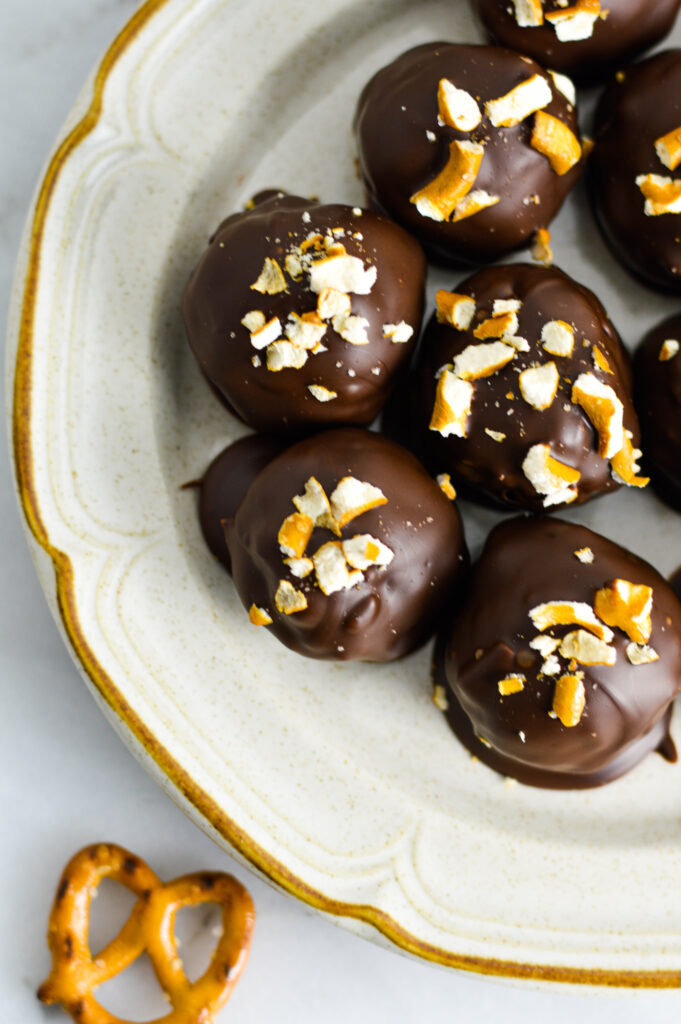 A small plate with chocolate coated peanut butter truffles topped with crushed pretzels.