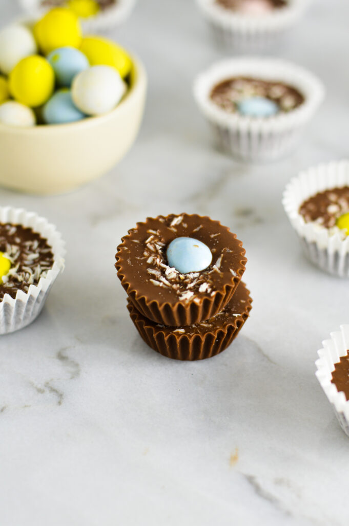 Two Easter Nest Nutella Cups stacked with a small bowl of Cadbury Mini Eggs in the background.