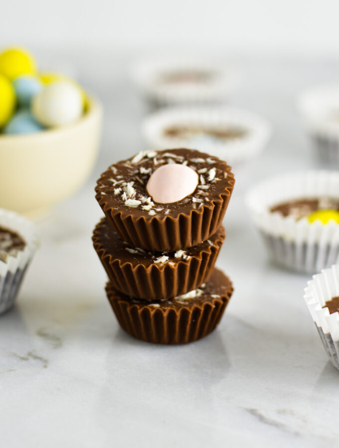 Three Coconut Mini Egg Nutella Cups stacked with more in the background as well as some chocolate Easter eggs.