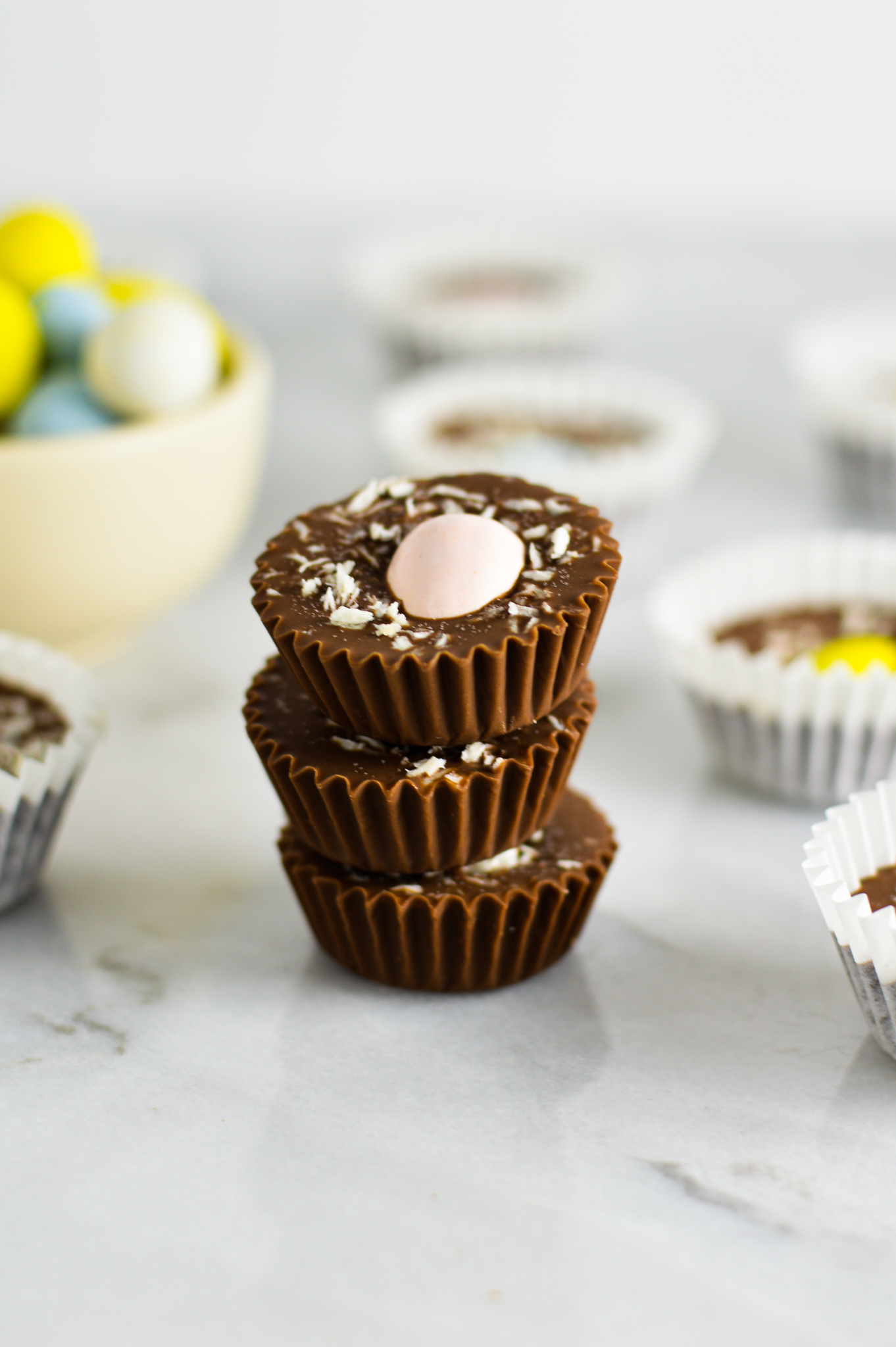 Three Coconut Mini Egg Nutella Cups stacked with more in the background as well as some chocolate Easter eggs.