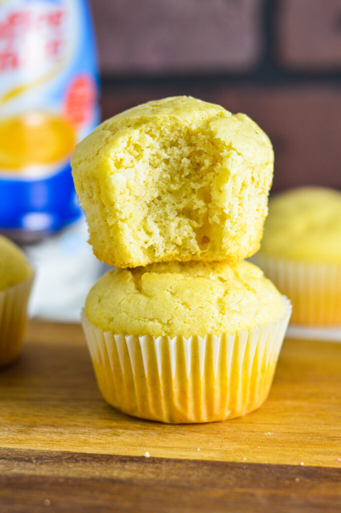 Two Vanilla Creamer Muffins stacked on top of each other with a bite taken out of the top one.